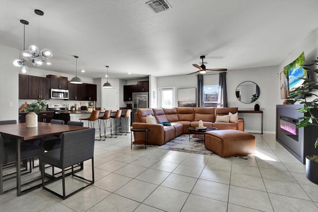 tiled living room with ceiling fan with notable chandelier