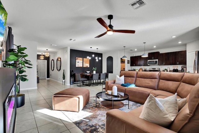 tiled living room with ceiling fan with notable chandelier