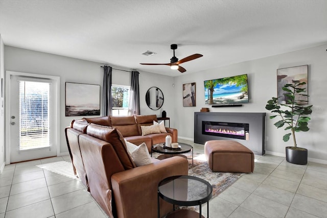 living room featuring ceiling fan, light tile patterned flooring, and a textured ceiling