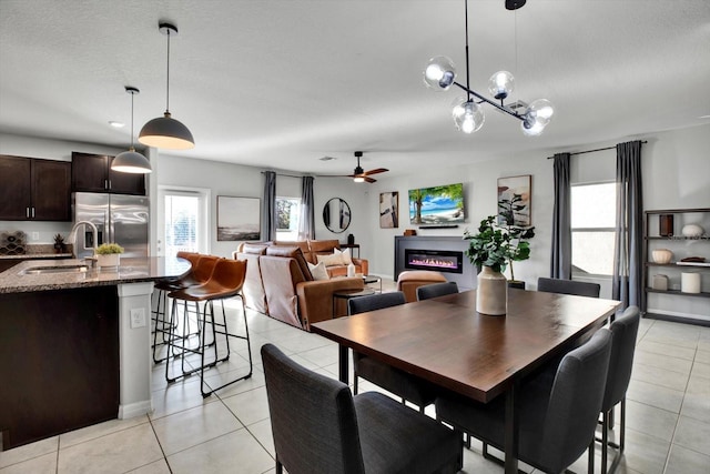 tiled dining room featuring ceiling fan with notable chandelier, a textured ceiling, and sink