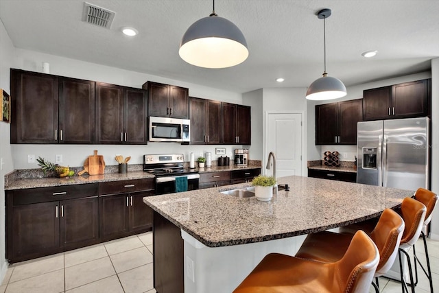 kitchen featuring appliances with stainless steel finishes, a center island with sink, pendant lighting, and sink