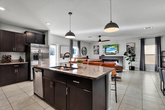 kitchen with pendant lighting, a kitchen island with sink, sink, and stainless steel appliances