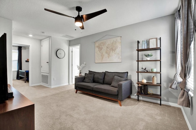 living room with a textured ceiling, light colored carpet, and ceiling fan