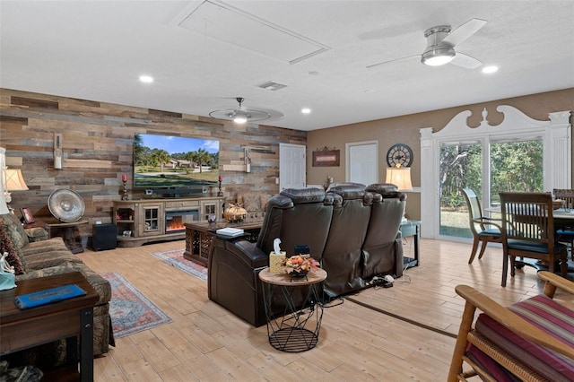 living room with ceiling fan, wood walls, and light hardwood / wood-style flooring