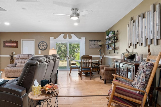 living room with ceiling fan and a textured ceiling