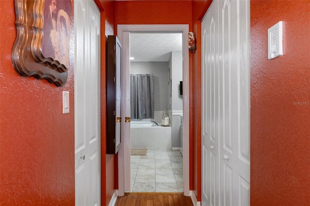 corridor featuring wood-type flooring and a textured ceiling