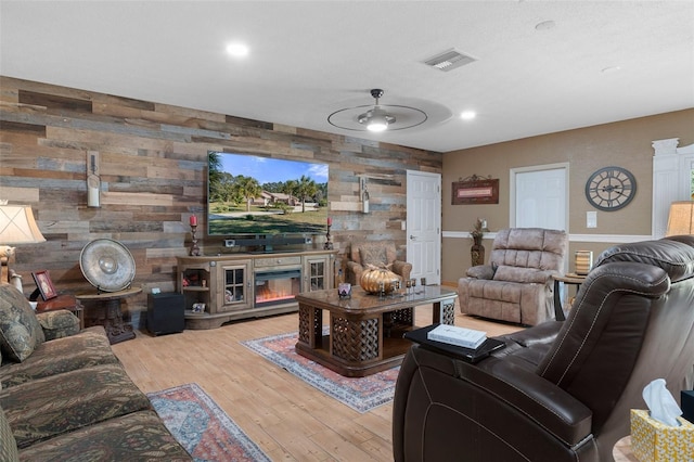 living room with wood walls, light hardwood / wood-style flooring, and ceiling fan