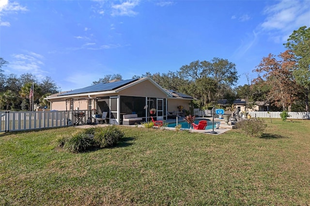 back of house featuring a sunroom, solar panels, a fenced in pool, and a yard