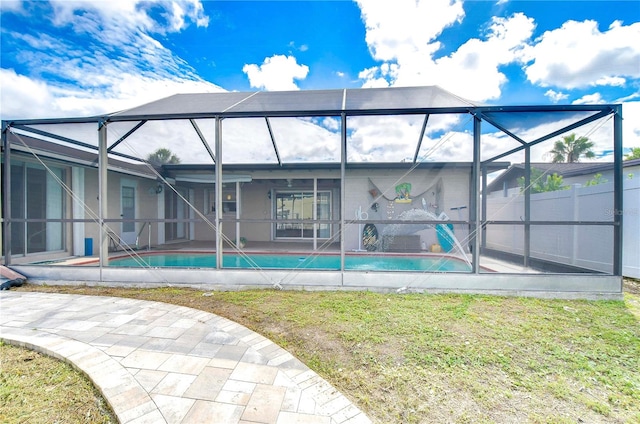 back of property featuring glass enclosure, a patio area, and a lawn