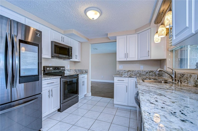 kitchen with stainless steel appliances, sink, light tile patterned floors, decorative light fixtures, and white cabinets