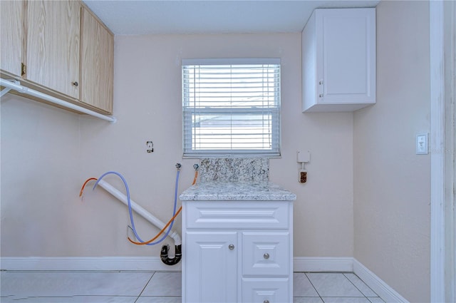 laundry area with hookup for a washing machine, light tile patterned floors, and cabinets