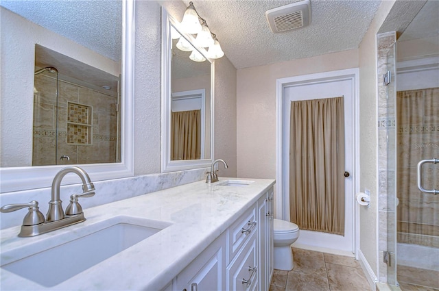 bathroom with a shower with door, vanity, a textured ceiling, and toilet