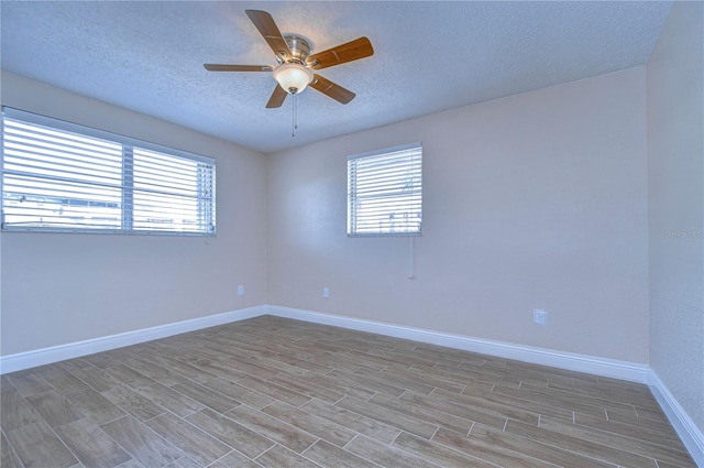 spare room featuring a textured ceiling, ceiling fan, and a healthy amount of sunlight