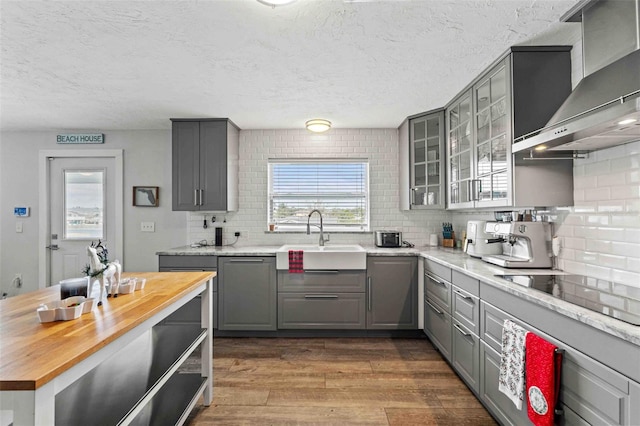 kitchen with gray cabinetry, sink, wall chimney range hood, and black electric stovetop