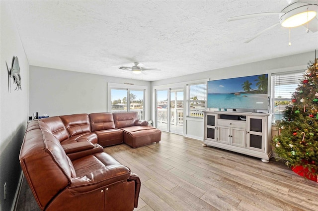 living room featuring a wealth of natural light, light hardwood / wood-style flooring, ceiling fan, and a textured ceiling