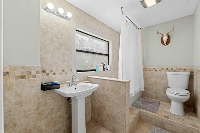 bathroom with sink, toilet, tile walls, and walk in shower