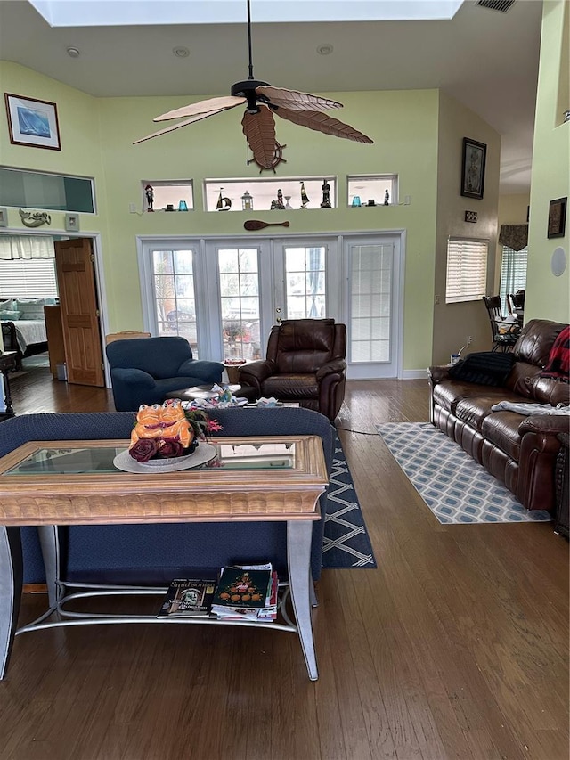 living room featuring ceiling fan, dark hardwood / wood-style floors, and a skylight