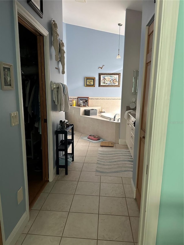 bathroom with tile patterned flooring, vanity, and tiled bath