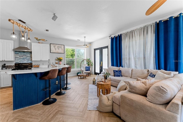 living room with ceiling fan, sink, light parquet flooring, and french doors