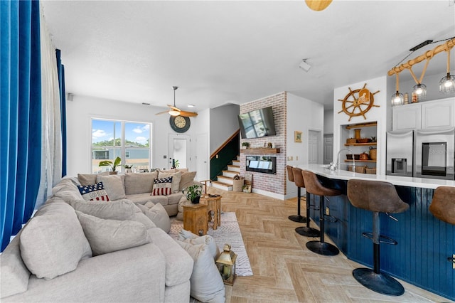 living room featuring a fireplace, light parquet flooring, and ceiling fan