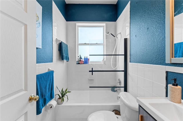 full bathroom featuring vanity, toilet, tile walls, and tiled shower / bath combo