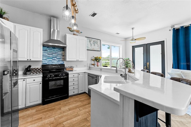 kitchen featuring a breakfast bar, kitchen peninsula, wall chimney exhaust hood, appliances with stainless steel finishes, and white cabinetry