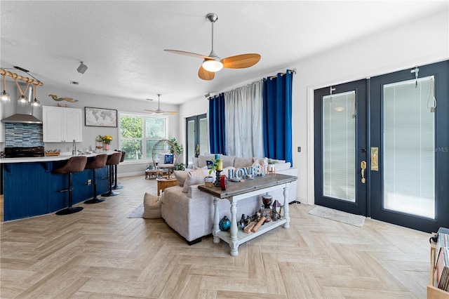 living room featuring ceiling fan, french doors, light parquet floors, and sink