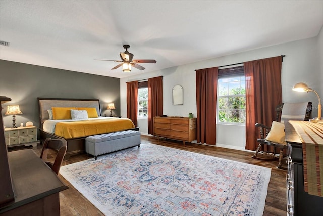 bedroom with multiple windows, ceiling fan, and dark hardwood / wood-style flooring