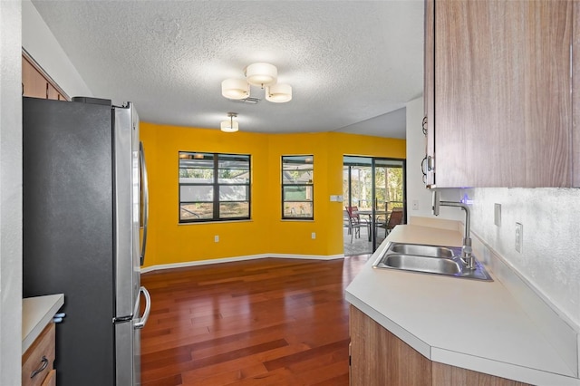 kitchen featuring a textured ceiling, stainless steel refrigerator, sink, and dark hardwood / wood-style floors