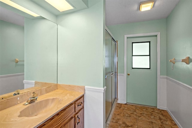 bathroom featuring a textured ceiling, vanity, and an enclosed shower