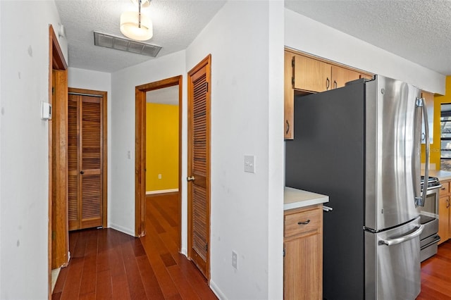 kitchen featuring appliances with stainless steel finishes, dark hardwood / wood-style flooring, and a textured ceiling