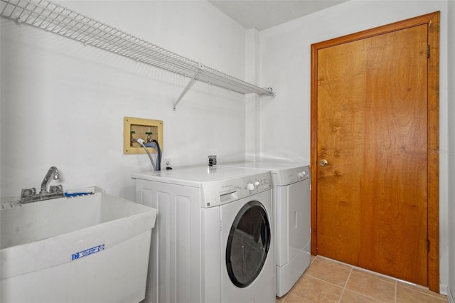 washroom with separate washer and dryer, sink, and light tile patterned floors