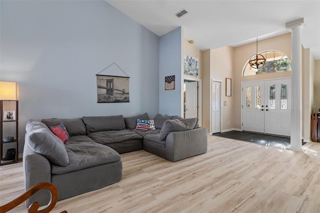 living room with light hardwood / wood-style flooring, high vaulted ceiling, and a chandelier