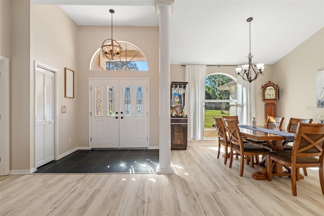 entryway with a notable chandelier, wood-type flooring, and decorative columns