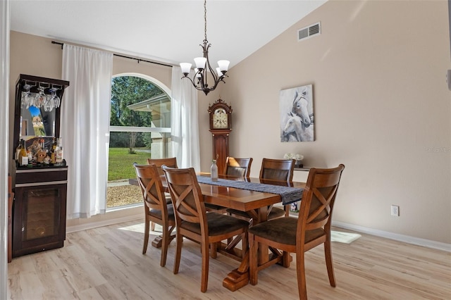 dining room featuring light hardwood / wood-style floors, lofted ceiling, and a notable chandelier