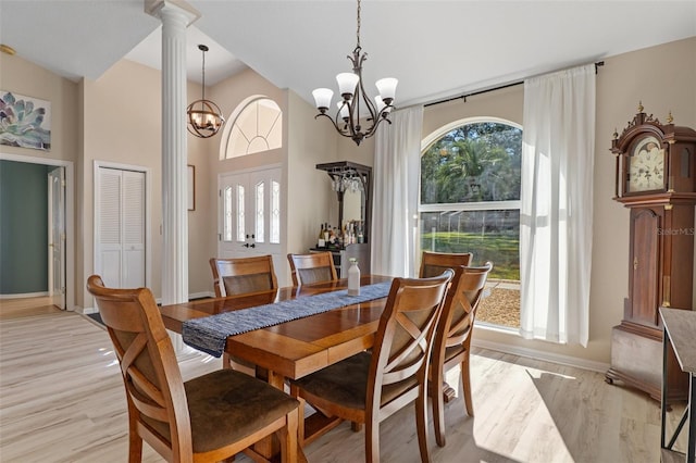 dining area with light wood-type flooring, decorative columns, plenty of natural light, and a notable chandelier