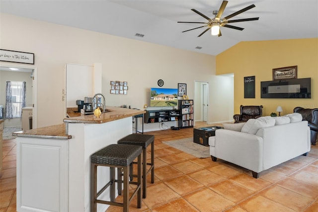 living room with ceiling fan, light tile patterned flooring, and lofted ceiling