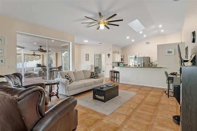 living room featuring ceiling fan, light tile patterned floors, and lofted ceiling with skylight