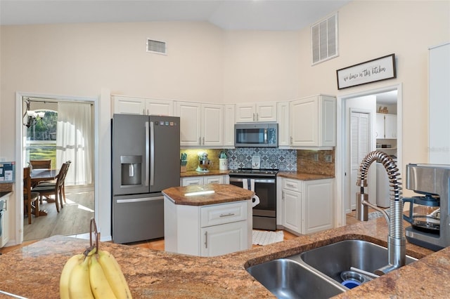 kitchen with white cabinetry, sink, a center island, stainless steel appliances, and decorative backsplash