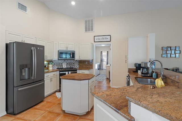 kitchen with white cabinetry, sink, kitchen peninsula, dark stone counters, and appliances with stainless steel finishes