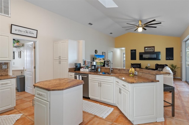 kitchen with white cabinets, vaulted ceiling with skylight, sink, dishwasher, and a center island