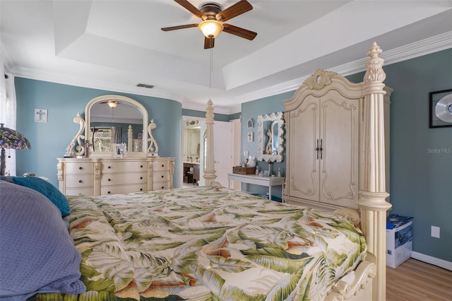 bedroom with ceiling fan, light hardwood / wood-style flooring, and a tray ceiling