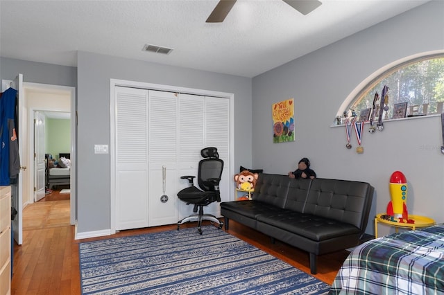 bedroom featuring hardwood / wood-style flooring, ceiling fan, a textured ceiling, and a closet