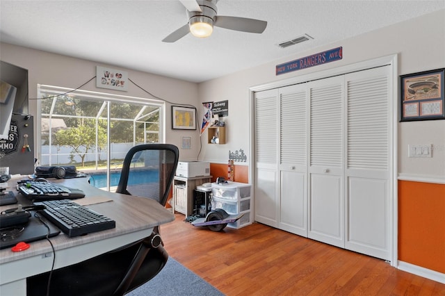 home office featuring ceiling fan, light wood-type flooring, and a textured ceiling