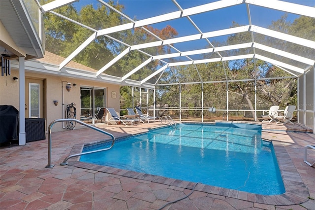 view of swimming pool with a grill, a patio area, and a lanai