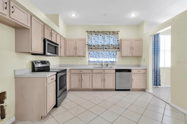 kitchen featuring light tile patterned floors, light brown cabinetry, appliances with stainless steel finishes, and sink