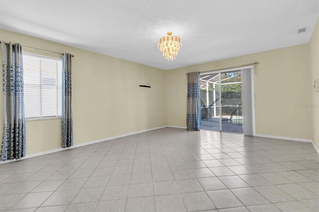 spare room with light tile patterned flooring and a chandelier