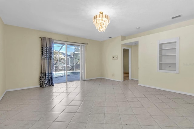 spare room featuring a notable chandelier, light tile patterned flooring, and built in shelves