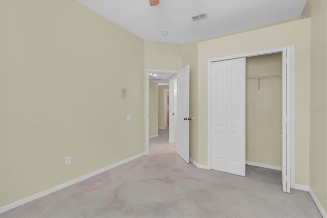 unfurnished bedroom with light carpet, ceiling fan, and a closet