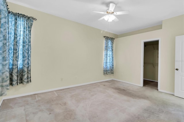 unfurnished bedroom featuring ceiling fan, a closet, a spacious closet, and light carpet